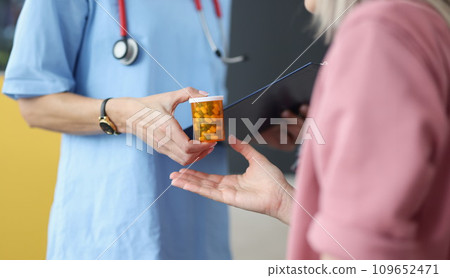 Doctor giving jar of pills to patient closeup Doctor giving jar of pills to patient closeup 109652471