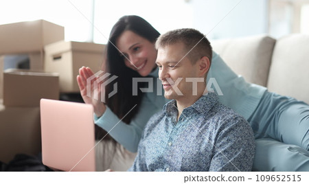 Man and woman looking at laptop screen and waving hand 109652515