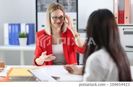 Business woman with glasses communicating with colleague at table 109654423