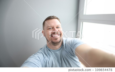Young smiling man taking selfie at home 109654478