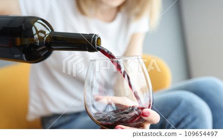 Woman pouring red wine into glass closeup 109654497