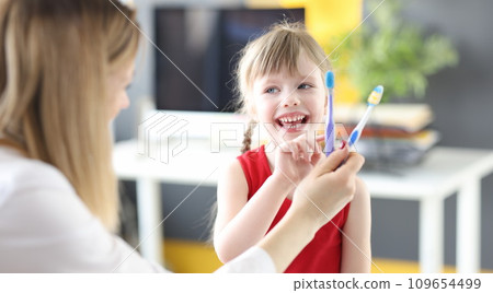 Little girl choosing toothbrush at dentists office Little girl choosing toothbrush at dentists office 109654499