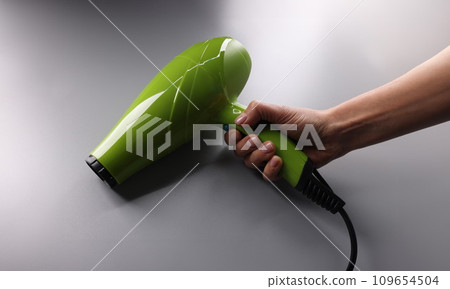 Woman holding green hair dryer in hand closeup Woman holding green hair dryer in hand closeup 109654504