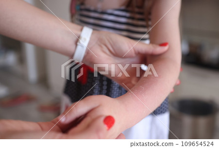 Woman holding child hand with sunburn closeup Woman holding child hand with sunburn closeup 109654524