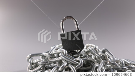 Solid metal locked padlock on top of tangled silver chain 109654668