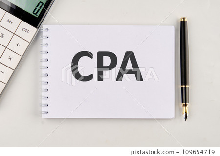 CPA, Certified Public Accountant or Cost per Action the inscription on the notebook next to the calculator and pen 109654719