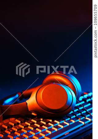 Headphones on a computer keyboard on black background Headphones on a computer keyboard on black background 109655709