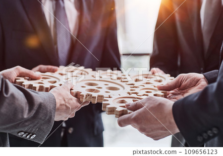 Business people holding wooden gears in office 109656123