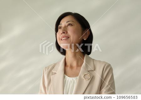 Smiling middle-aged woman wearing a pearl brooch 109656583