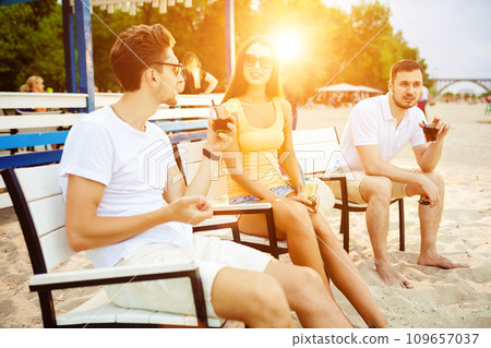 Young people enjoying summer vacation sunbathing drinking at beach bar Young people enjoying summer vacation sunbathing drinking at beach bar 109657037