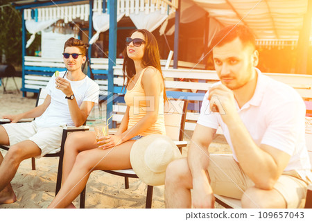 Young people enjoying summer vacation sunbathing drinking at beach bar Young people enjoying summer vacation sunbathing drinking at beach bar 109657043