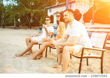 Young people enjoying summer vacation sunbathing drinking at beach bar Young people enjoying summer vacation sunbathing drinking at beach bar 109657045
