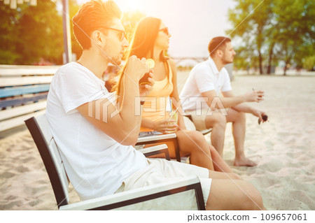 Young people enjoying summer vacation sunbathing drinking at beach bar Young people enjoying summer vacation sunbathing drinking at beach bar 109657061