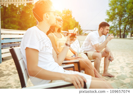 Young people enjoying summer vacation sunbathing drinking at beach bar Young people enjoying summer vacation sunbathing drinking at beach bar 109657074
