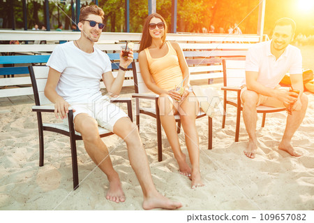 Young people enjoying summer vacation sunbathing drinking at beach bar Young people enjoying summer vacation sunbathing drinking at beach bar 109657082