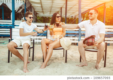 Young people enjoying summer vacation sunbathing drinking at beach bar Young people enjoying summer vacation sunbathing drinking at beach bar 109657093