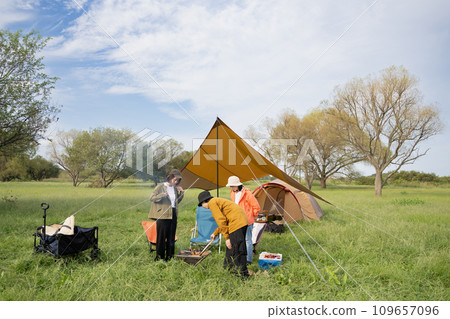 Outdoor image of young men and women enjoying camping and making a bonfire Outdoor image of young men and women enjoying camping and making a bonfire 109657096