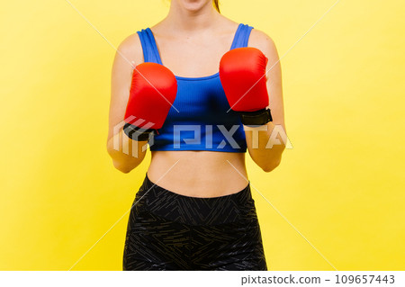 Woman boxer in gloves training on grey and yellow background Woman boxer in gloves training on grey and yellow background 109657443