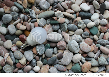 Energy Saving Lamp Bulb On A Colored Smooth Pebbles Texture Background Energy Saving Lamp Bulb On A Colored Smooth Pebbles Texture Background 109657863