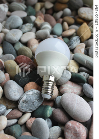 Vertical Photo Of LED Bulb With E14 Basement Lying On Smooth Sea Stones Vertical Photo Of LED Bulb With E14 Basement Lying On Smooth Sea Stones 109657864