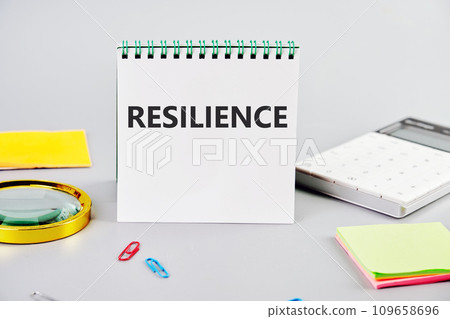 RESILIENCE the inscription on the notebook on a gray background next to the stationery RESILIENCE the inscription on the notebook on a gray background next to the stationery 109658696