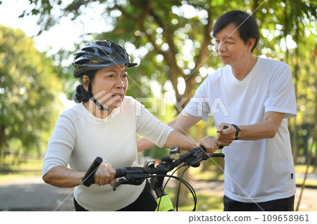 Shot of active senior couple riding bicycles in public park together. Healthy lifestyle concept. 109658961