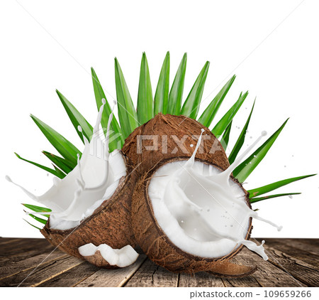 Cracked coconuts with splashing milk on old wooden table Cracked coconuts with splashing milk on old wooden table 109659266
