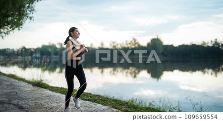 Jogging woman running in park on beautiful day off. Sport fitness model of asian ethnicity training outdoor for marathon Jogging woman running in park on beautiful day off. Sport fitness model of asian ethnicity training outdoor for marathon 109659554