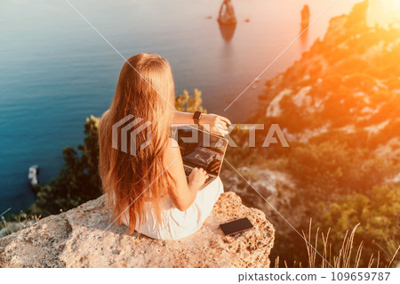 Freelance happy woman typing on her laptop, enjoying the picturesque sea view, highlighting the idea of working remotely with a relaxed and pleasant atmosphere. Freelance happy woman typing on her laptop, enjoying the picturesque sea view, highlighting the idea of working remotely with a relaxed and pleasant atmosphere. 109659787