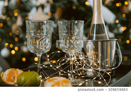 Champagne glasses, New Year decor. New Year's festive setting, family holidays.Two glasses of champagne are on the table against the background of New Year's decorated tree. 109659865