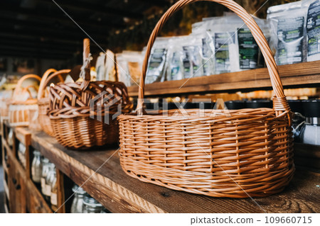 Wicker Baskets on Rustic Wooden Shelves. Assorted wicker baskets displayed on wooden shelving in a cozy, rustic Organic Food shop setting. 109660715