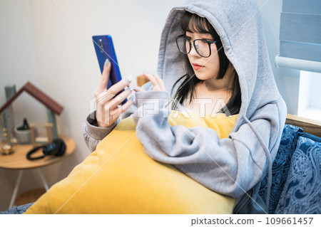 一位戴眼鏡的女士在床上看著智慧型手機 109661457