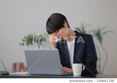 Business woman holding the corners of her eyes with tired eyes 1 109661786