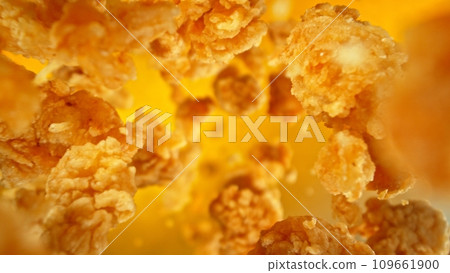 Freeze motion of flying pieces of fried chicken pieces on colored background. 109661900