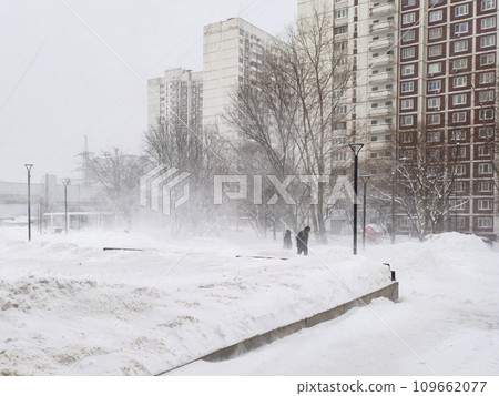 Silhouettes of people walking in a snowstorm through the city on a winter day. 109662077