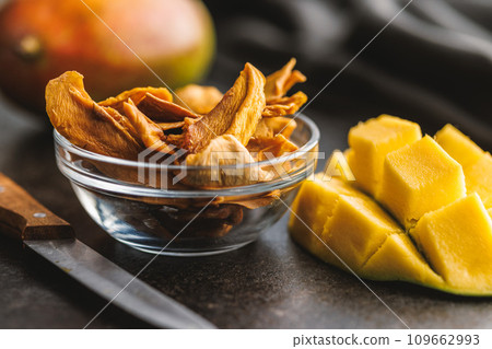 Dried mango fruit in bowl on black table. 109662993