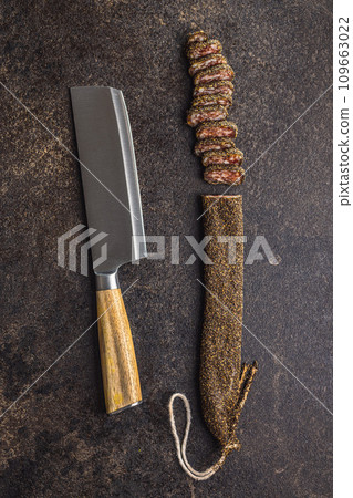 Smoked dried sausage. Sliced sausage on black table. Top view. Smoked dried sausage. Sliced sausage on black table. Top view. 109663022