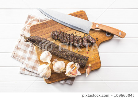 Smoked dried sausage. Sliced sausage on cutting board. To view. 109663045