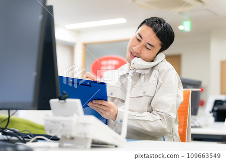 Employee answering the phone in the office Employee answering the phone in the office 109663549