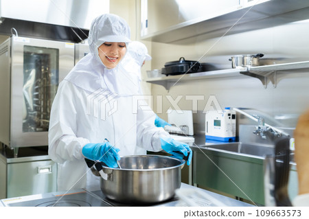 A woman in a white coat cooking in the kitchen 109663573