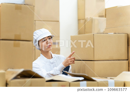 一名身穿白大褂的女士在倉庫檢查產品 109663577