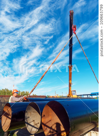 New pipes for gasification. Worker in construction helmet ships large-diameter metal pipes 109663799