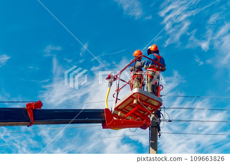 Two electricians from cradle of aerial platform or crane are repairing street lighting lamp Two electricians from cradle of aerial platform or crane are repairing street lighting lamp 109663826
