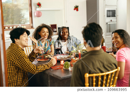 Happy friends enjoying in conversation and drinking wine during festive dinner at home party 109663995
