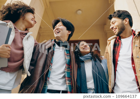 Group of happy young students are embracing while standing near university building 109664137