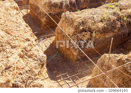 Constructing concrete foundation from digging an earthen trench Constructing concrete foundation from digging an earthen trench 109664165