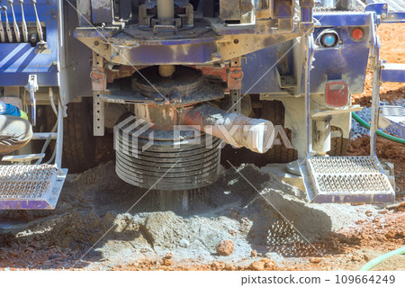 Workmen are drilling water well in suburban yard for artesian water by using drilling machine. 109664249