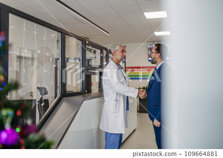 Grateful patient wishing doctor a merry Christmas after being discharged from the hospital, thanking for care. Mature male doctor working a Christmas shift in hospital, can't be with family during Grateful patient wishing doctor a merry Christmas after being discharged from the hospital, thanking for care. Mature male doctor working a Christmas shift in hospital, can't be with family during 109664881