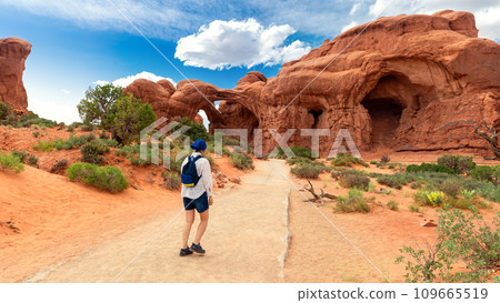 Woman Hiking to Double Arch in Utah National Park Woman Hiking to Double Arch in Utah National Park 109665519