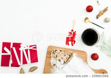 Christmas table with stollen cake, coffee cup, tree toys and gift boxes on white. Flat lay, top view. Christmas table with stollen cake, coffee cup, tree toys and gift boxes on white. Flat lay, top view. 109665998